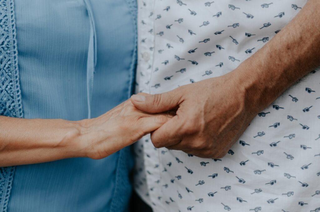 A younger person holding the hand of an older person
